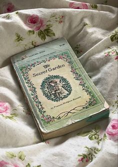 a book sitting on top of a bed covered in pink roses and green trimmings