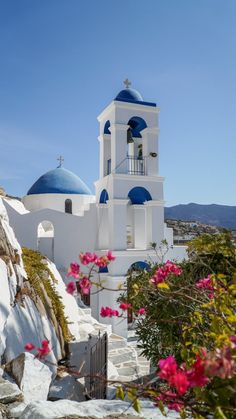 a white church with blue domes and pink flowers