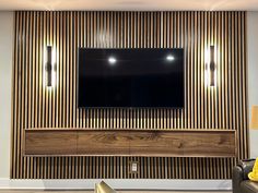 a living room with a large tv mounted on the wall and wooden paneling behind it