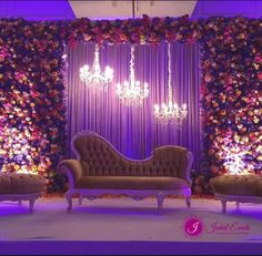 a stage set up with couches, chandeliers and flowers on the wall