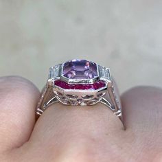 A stunning gemstone ring that features a 4.18 carat emerald cut kunzite with a beautiful pink hue. The center stone is flanked by two baguette cut diamonds with a combined weight of approximately 0.40 carats. Surrounding the kunzite is a halo of French-cut rubies weighing approximately 0.42 carats total. Approximately 0.16 carats of round brilliant cut diamonds are set along the tapered shoulders. This ring is handcrafted in platinum and adorned with fine milgrain. The under-gallery is decorated Jupiter Jewelry, Kunzite Ring, Bezel Set Diamond Ring, Estate Diamond Jewelry, Vintage Jewelry Antique, Vintage Cocktail Ring, French Cut, Jewelry Antique, Bezel Set Diamond