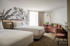 a hotel room with two beds and a chair in front of the bed is decorated with palm trees