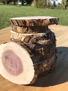 a stack of logs sitting on top of a wooden table next to a green field