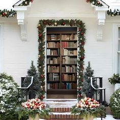 a white house decorated for christmas with bookshelves and wreaths on the front door