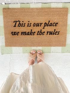 a person standing in front of a door mat that says, this is our place we make the rules