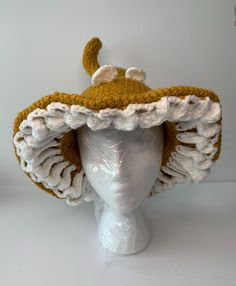 a white mannequin head wearing a brown and white crocheted hat