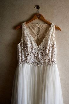 a white dress hanging on a wooden hanger