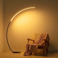 a chair with a blanket on it next to a light that is turned on by a lamp