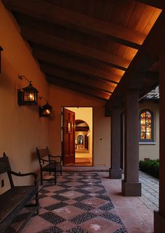 an entry way with two benches and lanterns hanging from the ceiling, along with tiled flooring