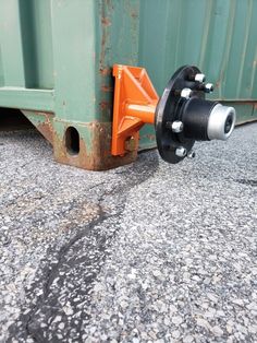 an orange and black object sitting on the ground next to a green dumpster truck