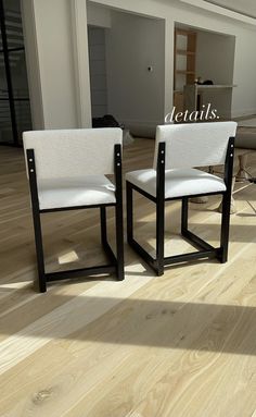 two white chairs sitting on top of a hard wood floor