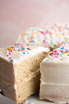 a cake with white frosting and sprinkles cut in half on a plate