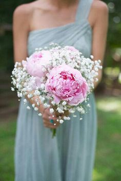 a bridesmaid holding a bouquet of pink flowers and baby's breath in her hand