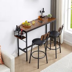 a table with two stools and some bottles on it next to a couch in front of a window