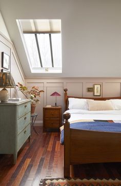 a bed room with a neatly made bed next to a dresser and lamp on top of it