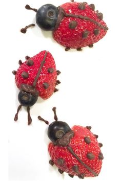 three little ladybugs sitting on top of each other with strawberries in them