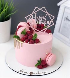 a pink cake decorated with raspberries and icing