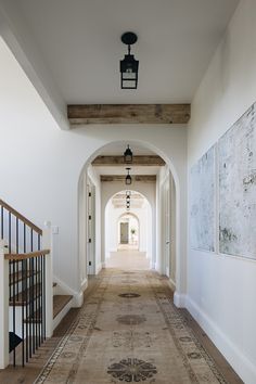 the hallway is lined with antique rugs and art on the walls, along with an entry way leading to another room