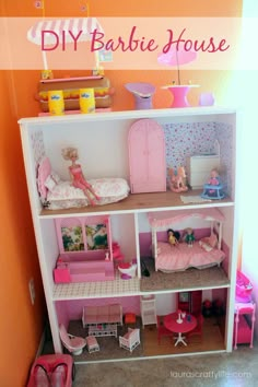 a doll house with pink furniture and accessories on the shelves in front of an orange wall