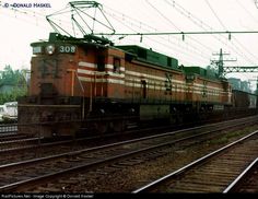 an orange train traveling down tracks next to power lines