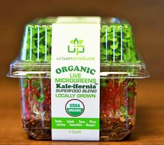 organic microgreens in a plastic container on a wooden table with the label above it