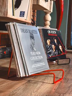 two books are sitting on the floor in front of a wooden table with an orange chair