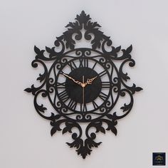 a black clock with gold hands on a white wall