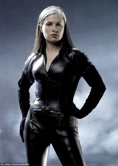 a woman in black leather is standing with her hands on her hips and looking at the camera