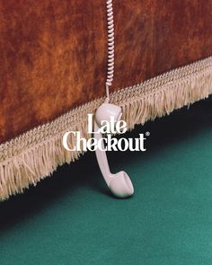 an old phone sitting on top of a green carpet next to a brown wall with the words late checkout