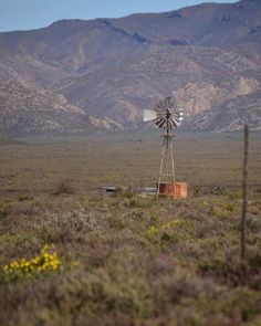 a windmill in the middle of a field with mountains in the background