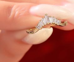 a close up of a person's hand holding a gold ring with diamonds on it