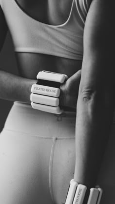 black and white photograph of a woman holding three books in her hand while wearing leggings