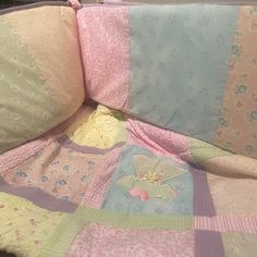 a baby crib with a quilted blanket and pillows on it's sides