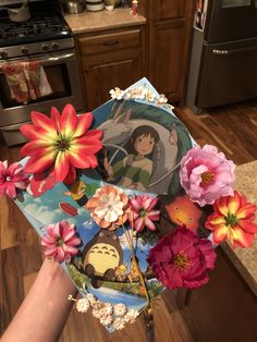 someone is holding up a paper plate with flowers on it and an image of totoro in the center