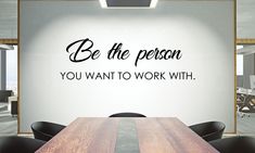 a wooden table sitting in front of a wall that says be the person you want to work with