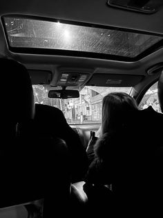 black and white photo of two people in the back seat of a car looking at something