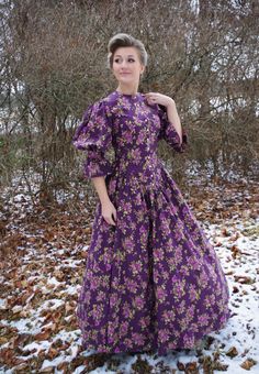 "You will find yourself looking for excuses to wear this lovely print dress! This Victorian styled dress has a high neckline at the front, and dips to a flattering \"V\" at the waistline. Buttons close the bodice at the front. The generously gathered skirt has pockets. The model is wearing a crinoline and boots and they are priced separately. 100% cotton. Hand or machine wash cold and tumble dry low. Recollections clothing is made in America.  The following are approximate finished measurements and include room for ease of movement.  BustWaist (in inches) XS36.528 S39        29.5 M41        31.5 L45        35.5 XL49        41 XXL51        44 3XL55.5        50 4XL59.556.5" Purple Fitted Maxi Dress For Casual Occasions, Fitted Purple Maxi Dress For Casual Occasions, Fitted Maxi Length Prairie Dress, Fitted Floral Print Prairie Dress, Fitted Floral Print Prairie Dress For Daywear, Fitted Prairie Dress For Daywear, Daywear Dress With Floral Print And Fitted Waist, Purple Floral Print Dress With Fitted Bodice, Fitted Floral Print Maxi Length Prairie Dress