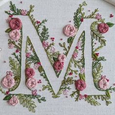 the letter m is made up of pink flowers and green leaves on a white background