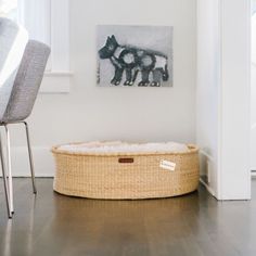 a dog bed in the corner of a room with a chair and pictures on the wall