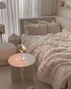 a white bed sitting in a bedroom next to a night stand with a lamp on it