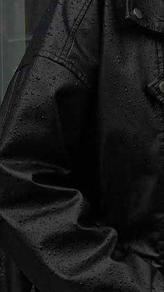 a man wearing a black leather jacket with rain drops on it