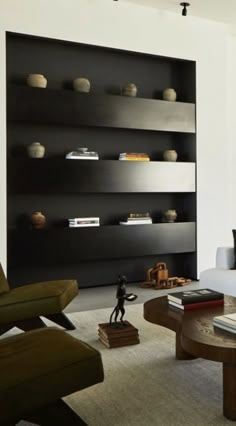 a modern living room with black and white furniture, bookshelves and shelves on the wall