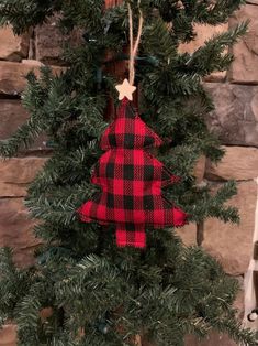 a red and black christmas tree ornament hanging on a wall next to a brick wall