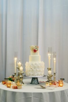 a white wedding cake sitting on top of a table next to candles and other decorations