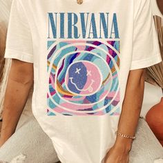 Nirvana Smiley Graphic Band Tee. Perfect For All Summer Long. Unisex Fit Makes It An Easy Throw On Top. Super Soft Feel. Color Is Vintage Off White. No Tags Attached. New Item. Sizing: Unisex Fit Bust Measurements From Manufacturer: Small 34-37” Medium 38-41” Large 42-45” X Large 46-49” 100% Cotton Made In Usa Colors May Appear Different In Photos Due To Lighting And Different Device Screens. Style Tags: Summer, Spring, Concert, Festival Season, Band Tee, Vintage, Beach, Grunge, 90s, Y2k, Colorf Festival Tshirt, Band Tee Style, Nirvana Tee, Band Tee Shirts, Graphic Band Tees, Retro Band, Vintage Band Tees, Concert Tees