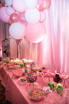 a table topped with lots of desserts and balloons in the air over it's head