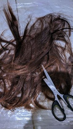 a pair of scissors sitting on top of a piece of hair