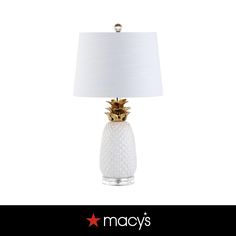 a white lamp with a gold pineapple on the bottom and a white shade over it