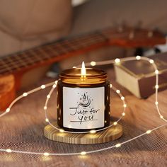 a lit candle sitting on top of a wooden table next to a string of lights