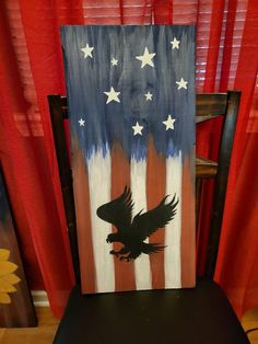 an eagle painted on the back of a chair in front of a red, white and blue american flag